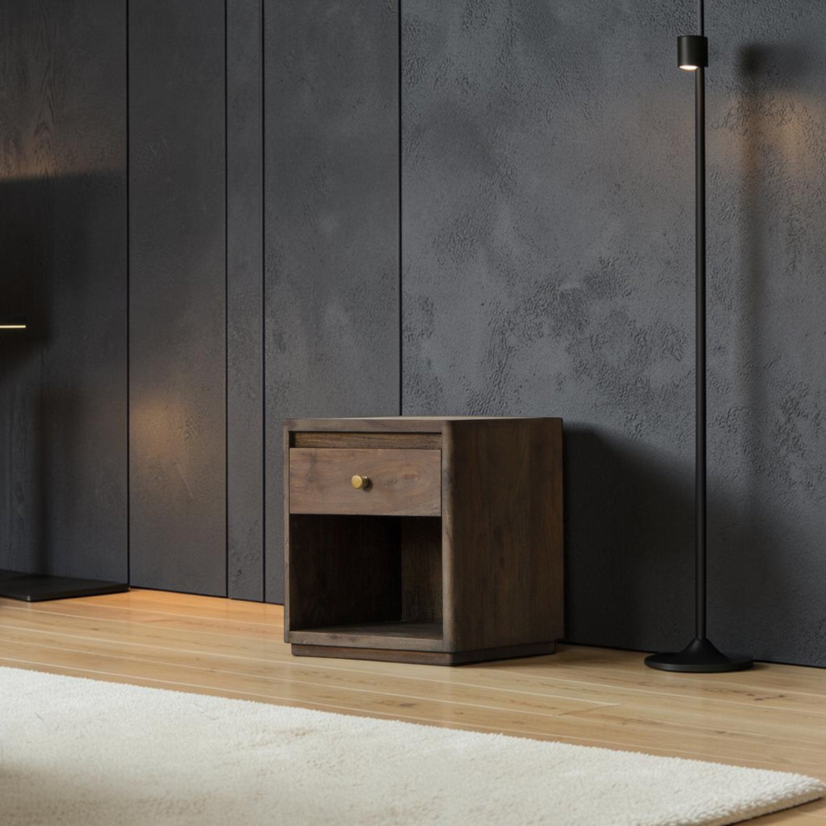 Homecrest Latimer bedside table in dark antiqued wood with a single drawer and open shelf against a dark wall.