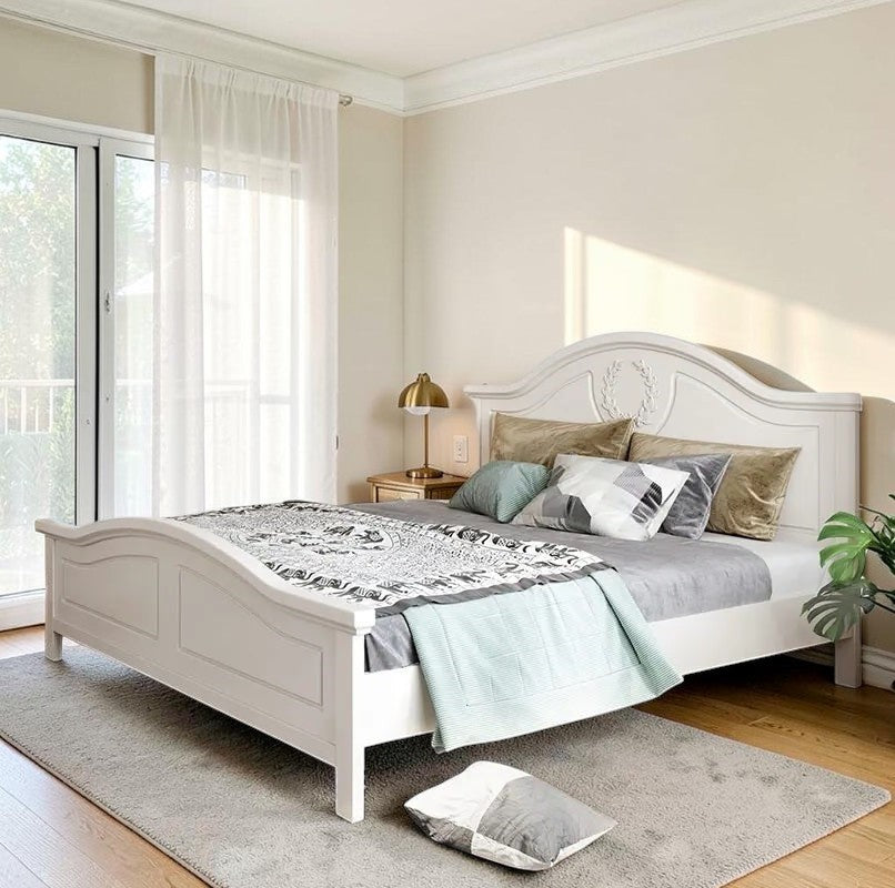 Homecrest light beige Sheesham wood bed with a curved headboard and decorative wreath carving in a bright bedroom