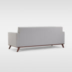 Homecrest Lindholm Scandinavian statement sofa in light grey fabric with a teak wood base viewed from the back