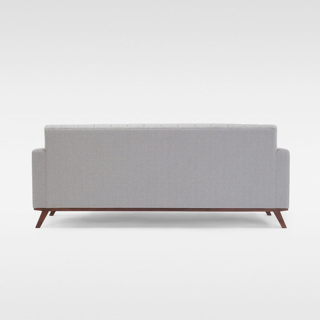Homecrest Lindholm Scandinavian statement sofa in light grey fabric with a teak wood base, back view.