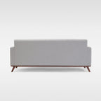 Homecrest Lindholm Scandinavian statement sofa in light grey fabric with a teak wood base, back view.