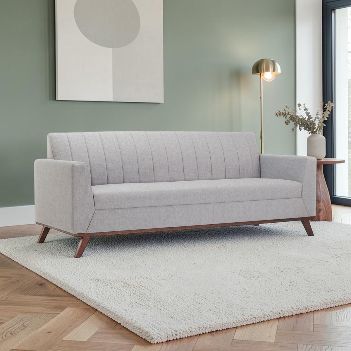 Homecrest Lindholm Scandinavian statement sofa in light grey fabric with a teak wood base in a modern living room.