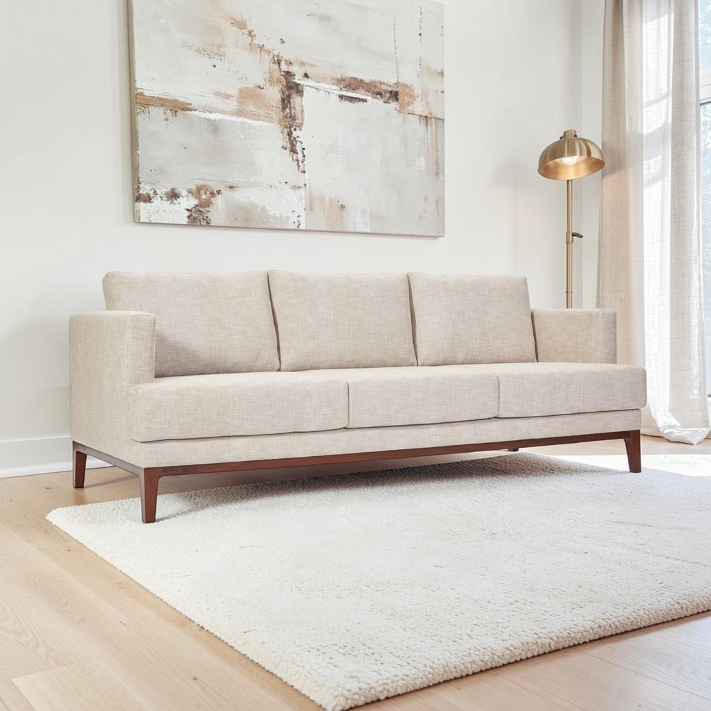 Homecrest Linnea contemporary sofa in parchment fabric with a slim profile and teak wood base in a bright living room.