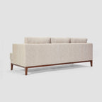 Homecrest Linnea contemporary sofa in parchment fabric with a slim profile and dark teak wood base, rear view.