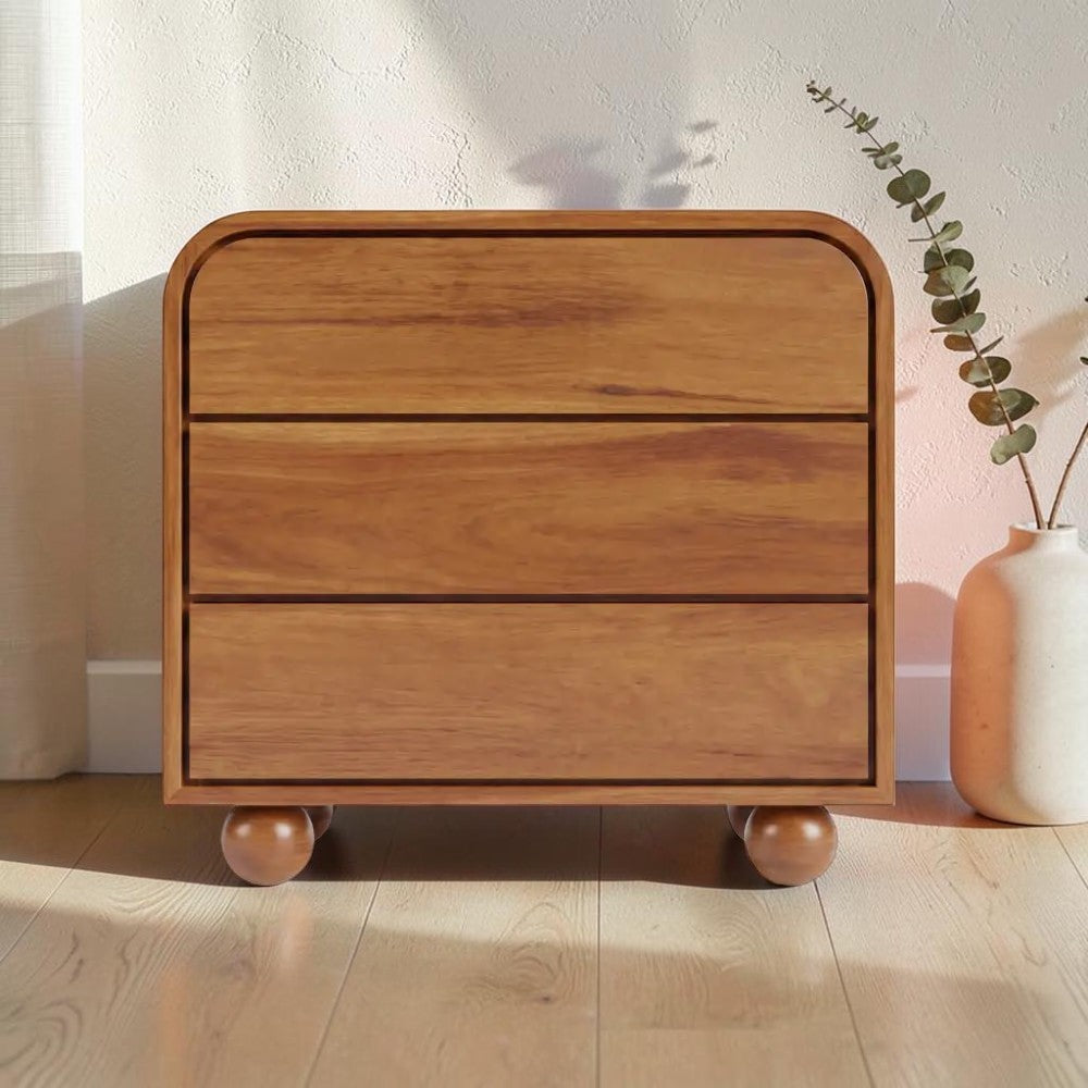 Homecrest Brisley 3-drawer chest in brown acacia wood with a rounded frame and spherical feet in a bright room.