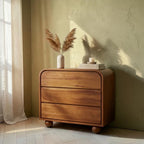 Homecrest Brisley 3-drawer dresser made of brown acacia wood with rounded edges and spherical feet in a sunlit room.