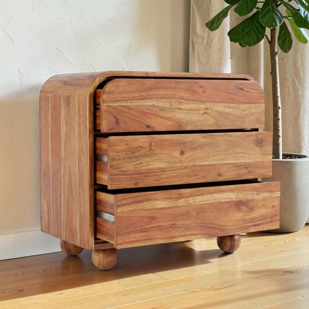Homecrest Brisley 3-drawer dresser in brown acacia wood with a curved frame and rounded feet in a bright room.