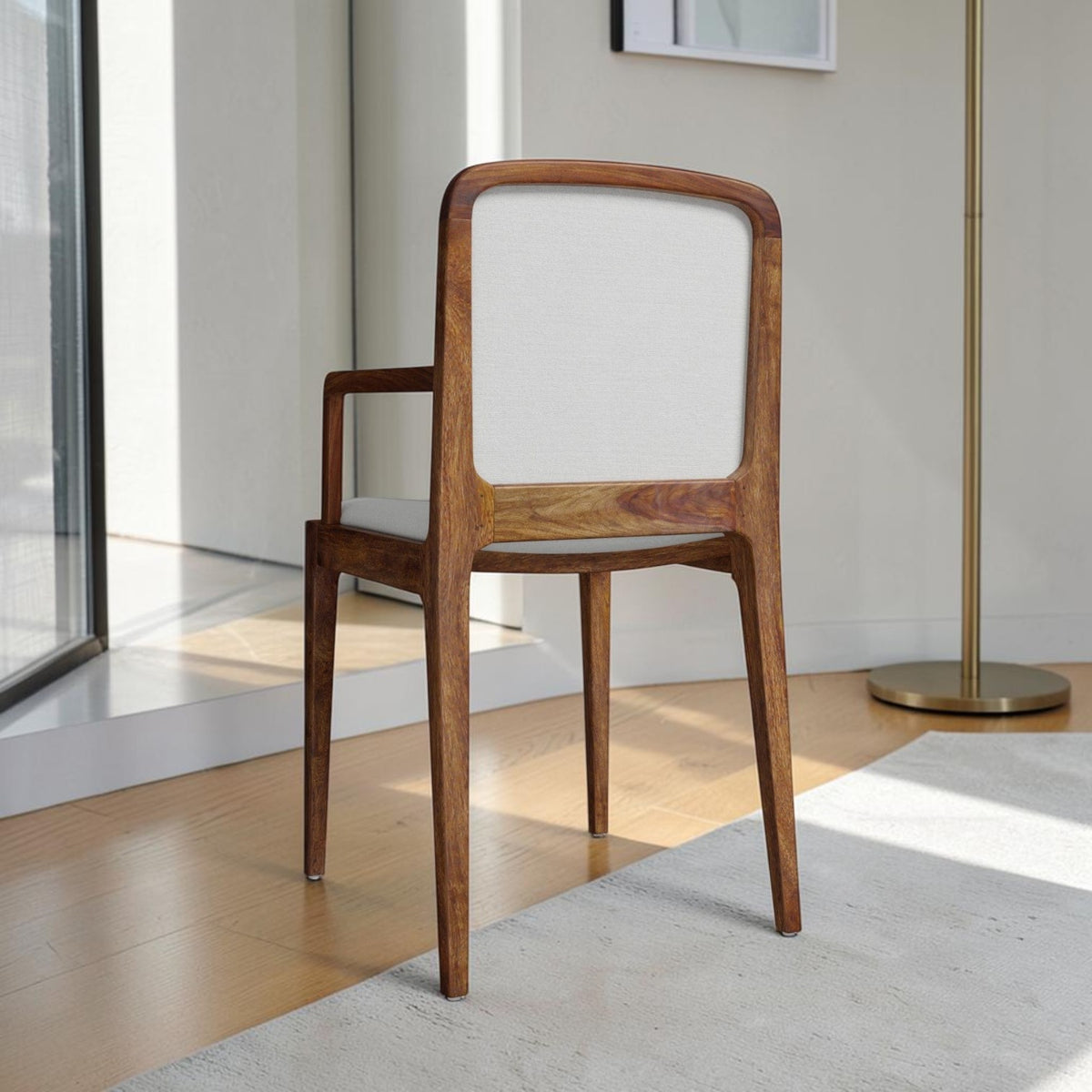 Homecrest Melbury teak wood dining chair with arms, featuring a natural wood frame and light cream upholstered back.