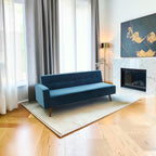 Homecrest mid-century button-down sofa in deep blue velvet, featuring tapered teak wood legs in a bright living room.