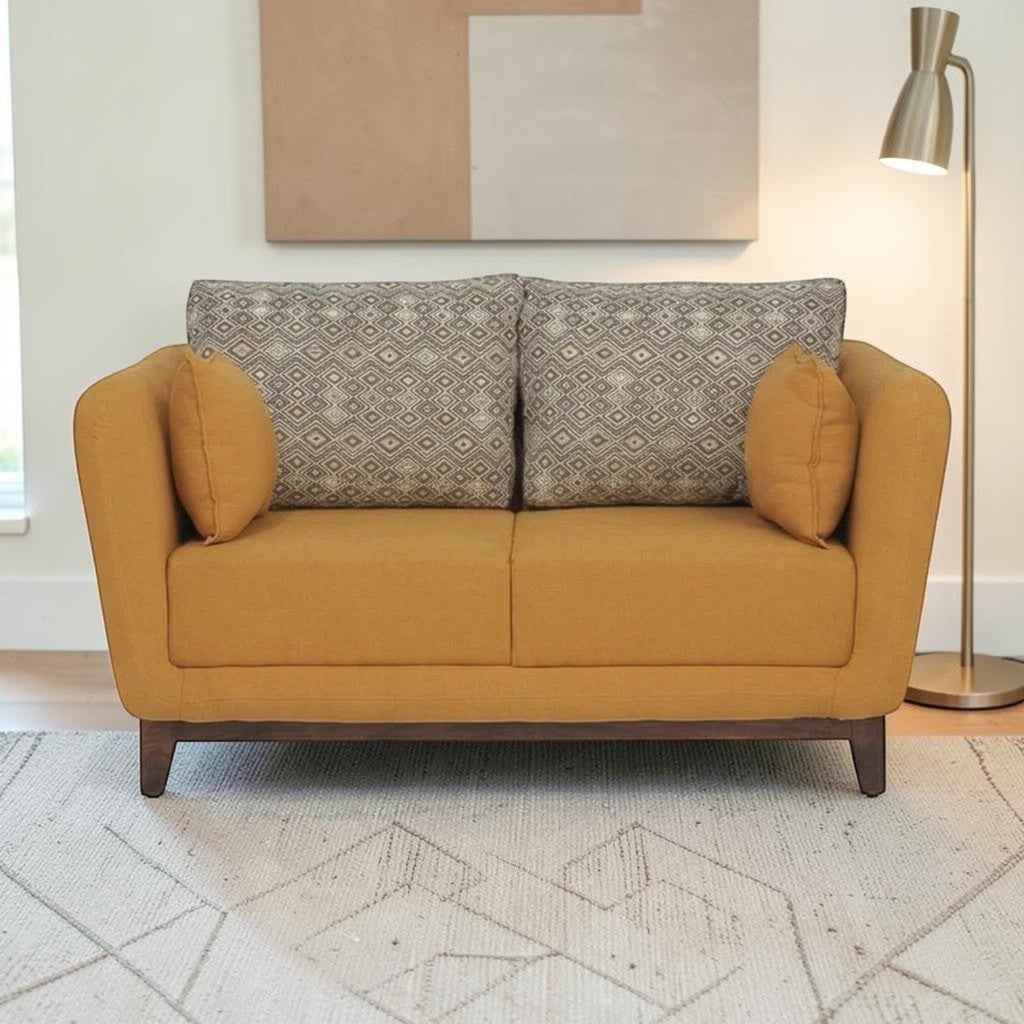 Homecrest modern 2-seater sofa in mustard fabric with patterned back cushions and solid wood base in a living room