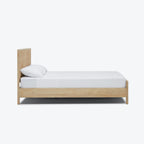 Homecrest natural mango wood bed frame with a woven rattan headboard and white bedding, side view