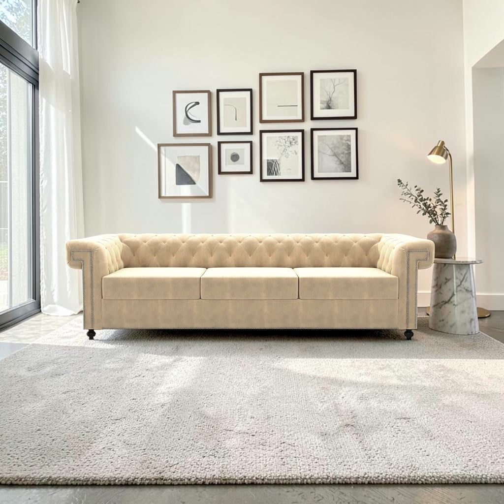 Homecrest Oakley three-seater Chesterfield sofa in beige velvet with button tufting and nailhead trim in a bright room.