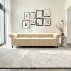 Homecrest Oakley three-seater Chesterfield sofa in beige velvet with button tufting and nailhead trim in a bright room.