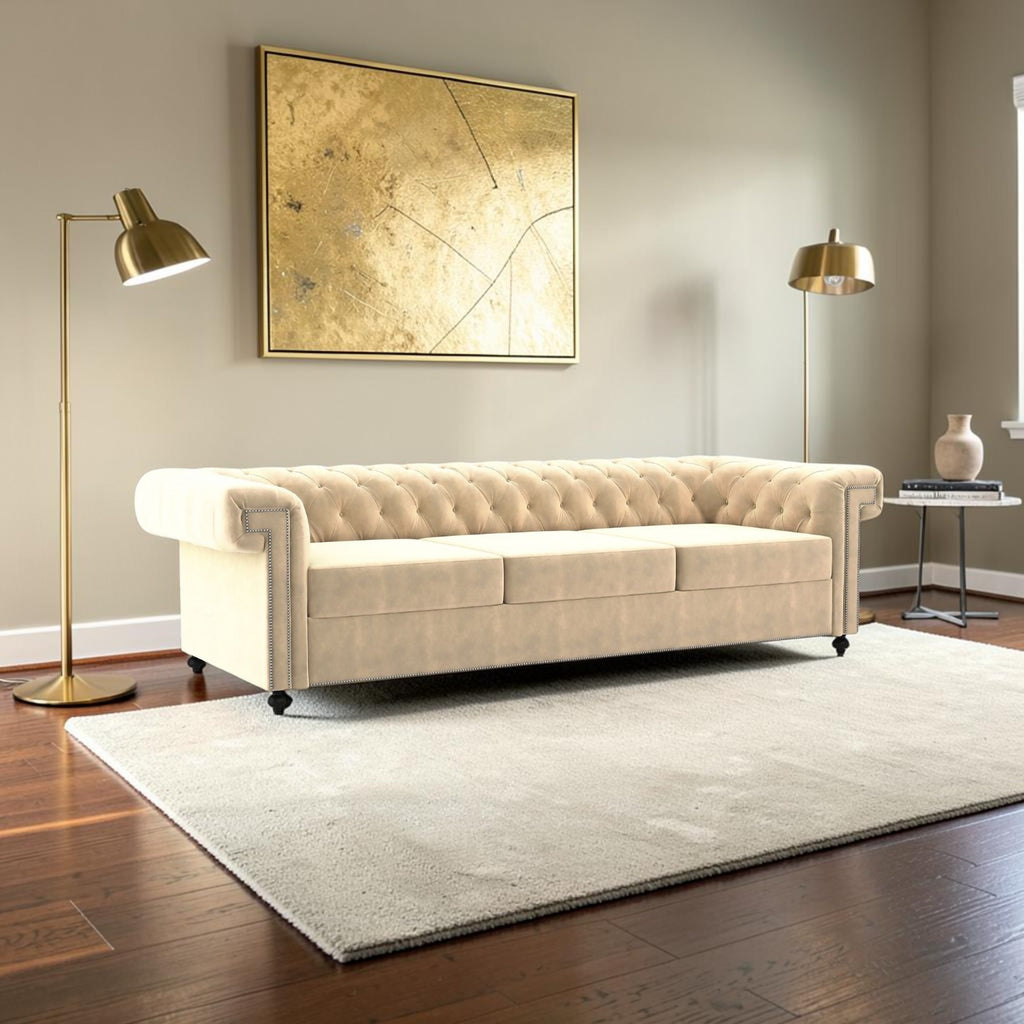 Homecrest Oakley three-seater Chesterfield sofa in beige velvet with tufted back and nailhead trim in a modern room.