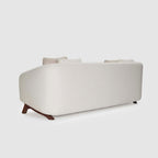 Homecrest Orbell wrap-arm curved sofa in cream fabric with sculptural dark teak wood legs, back view.