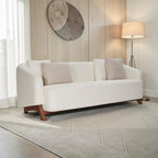 Homecrest Orbell wrap-arm curved sofa in cream fabric with teak wood legs and decorative accent cushions