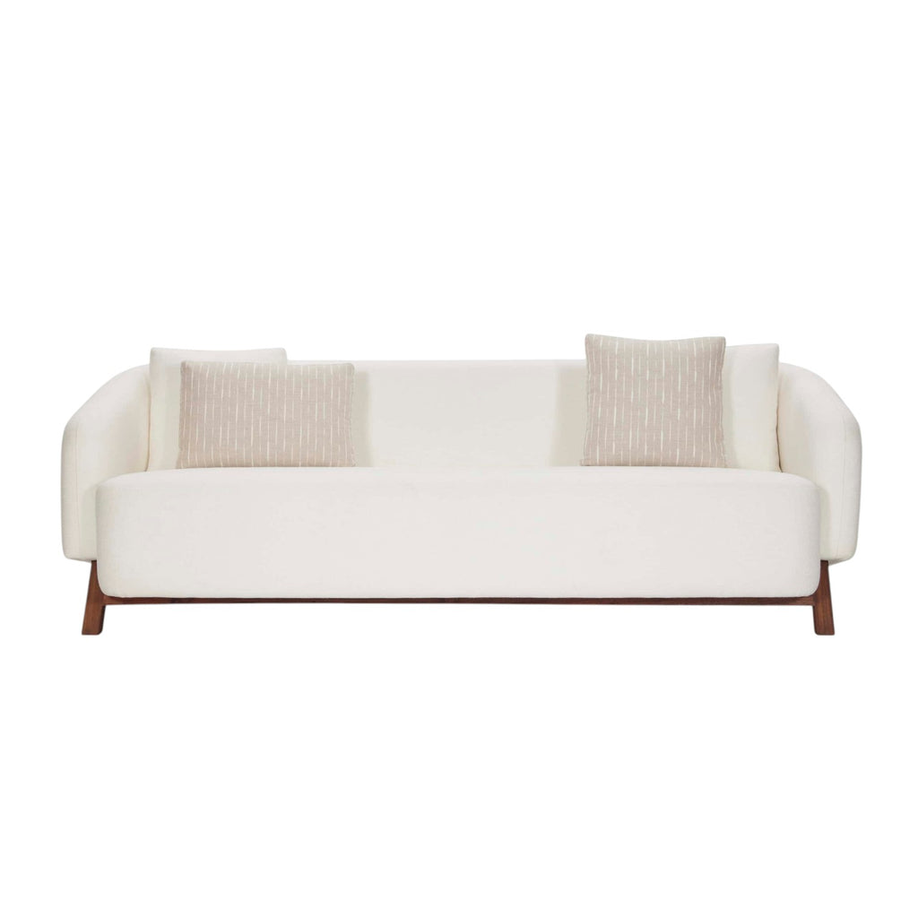 Homecrest Orbell wrap-arm curved sofa in cream fabric with sculptural teak wood legs and two decorative throw pillows.