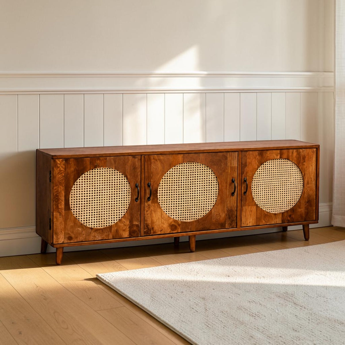 Homecrest Petra three-door media cabinet in honey-finished sheesham wood with round cane rattan door inserts.