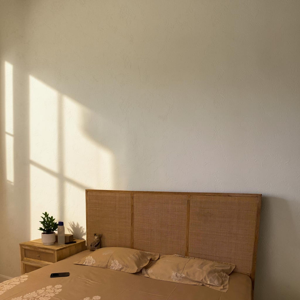 Homecrest natural mango wood bed with a woven rattan headboard in a sunlit bedroom setting