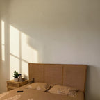 Homecrest natural mango wood bed with a woven rattan headboard in a sunlit bedroom setting