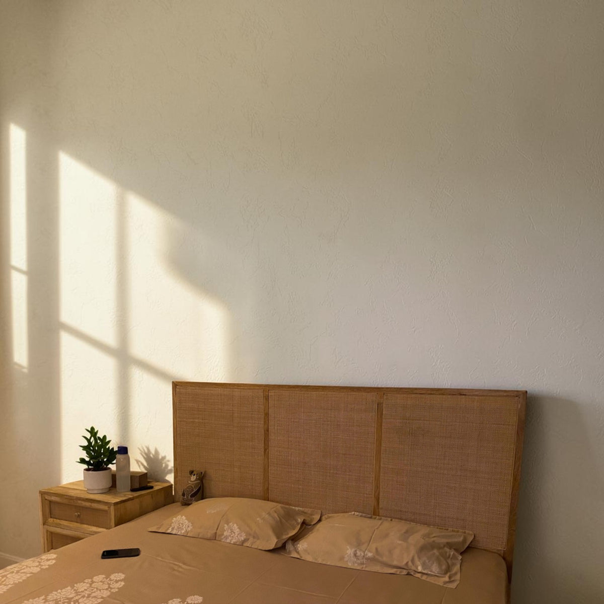 Homecrest natural mango wood bed with a woven rattan headboard in a sunlit bedroom setting