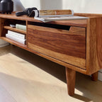 Homecrest Rowley solid wood media cabinet in a warm walnut finish with open shelving and a drawer