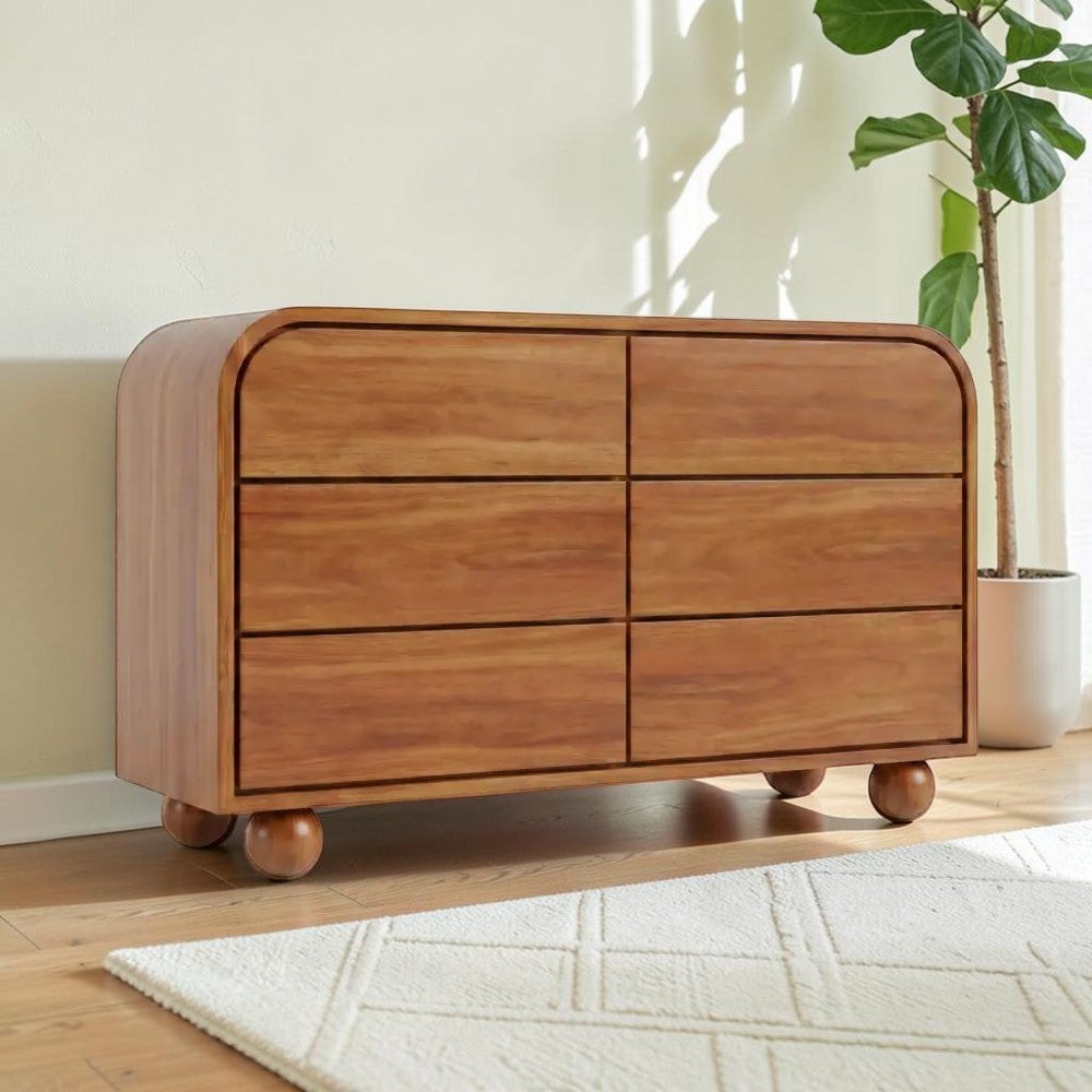 Homecrest Roswell 6-drawer dresser in warm brown acacia wood with rounded edges and spherical feet in a bright room.