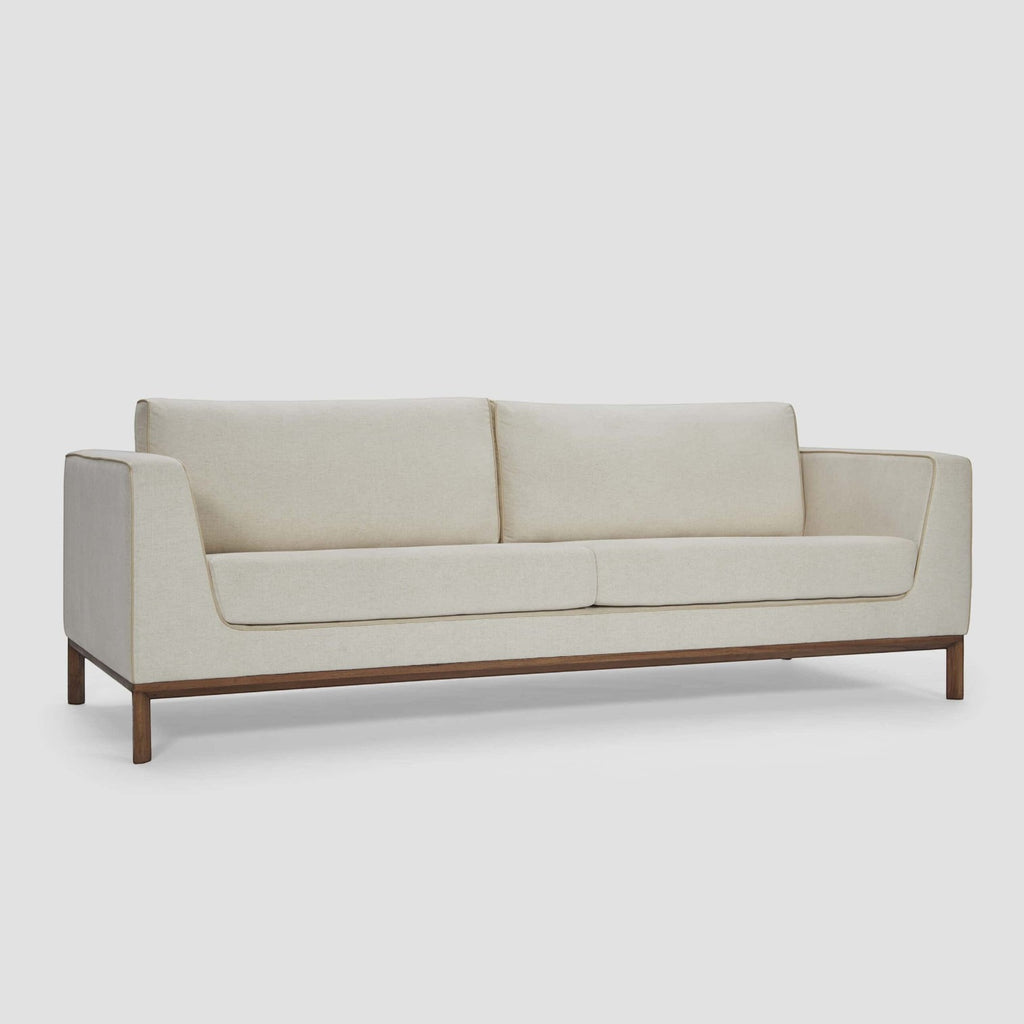 Homecrest Solace deep-seat lounge sofa in ivory fabric with contrast piping on a solid teakwood base frame.