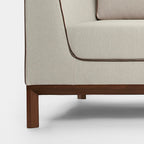 Homecrest Solace deep-seat lounge sofa in ivory fabric with brown contrast piping and a solid teakwood base frame.