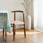 Homecrest Thornby dining chair crafted from natural teak wood with a hand-woven rattan wicker seat in a coastal setting.