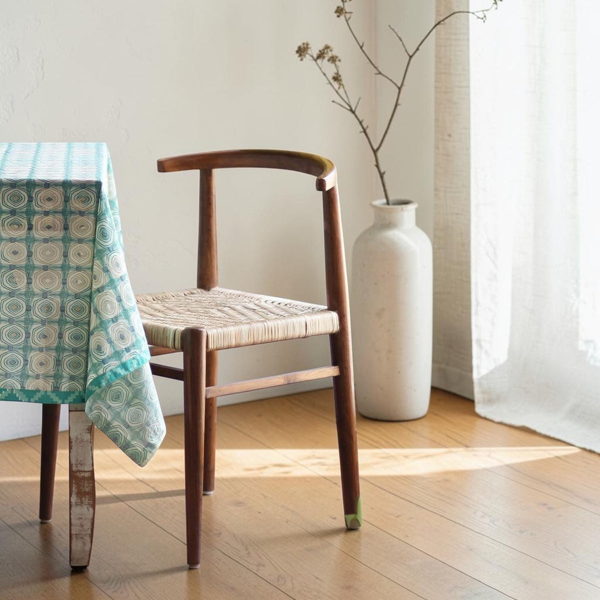 Homecrest Thornby dining chair crafted from natural teak wood with a hand-woven rattan wicker seat in a coastal setting.