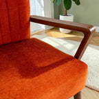 Homecrest Pelham armchair featuring vibrant orange fabric upholstery and a smooth, handcrafted seasoned teak wood frame.