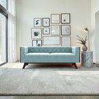 Homecrest Sturton velvet Chesterfield sofa in light blue with tufted backrest and dark wood legs in a modern living room