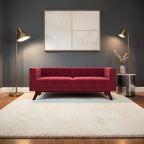 Homecrest Sturton Chesterfield sofa in pomegranate red velvet with button tufting and dark wooden legs in a modern room.