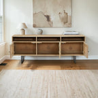 Homecrest Thayer media stand in natural mango wood with rattan detailing and open cabinet doors in a living room.