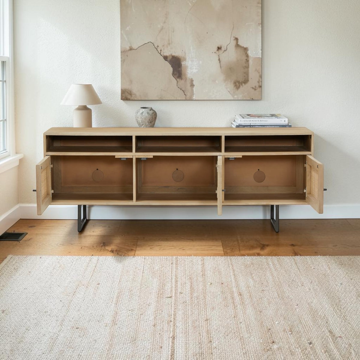 Homecrest Thayer media stand in natural mango wood with rattan detailing and open cabinet doors in a living room.