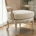 Homecrest Thakeham beige fabric armchair with a carved teak wood frame and rattan backrest detail.