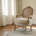 Homecrest Thakeham armchair with a carved teak wood frame, beige fabric seat, and rattan backrest in a bright room.