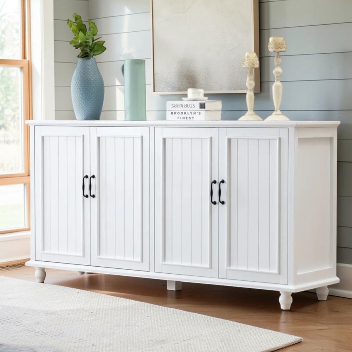 Homecrest Thorne four-door white sideboard with vertical paneling and black hardware in a bright living room setting.
