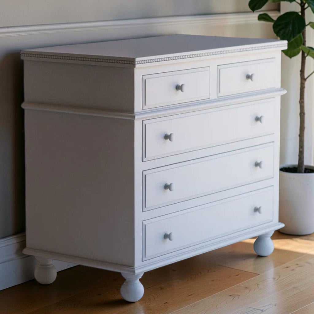 Homecrest white solid mango wood five-drawer chest with beaded moulding and bun-foot legs in a bright room.