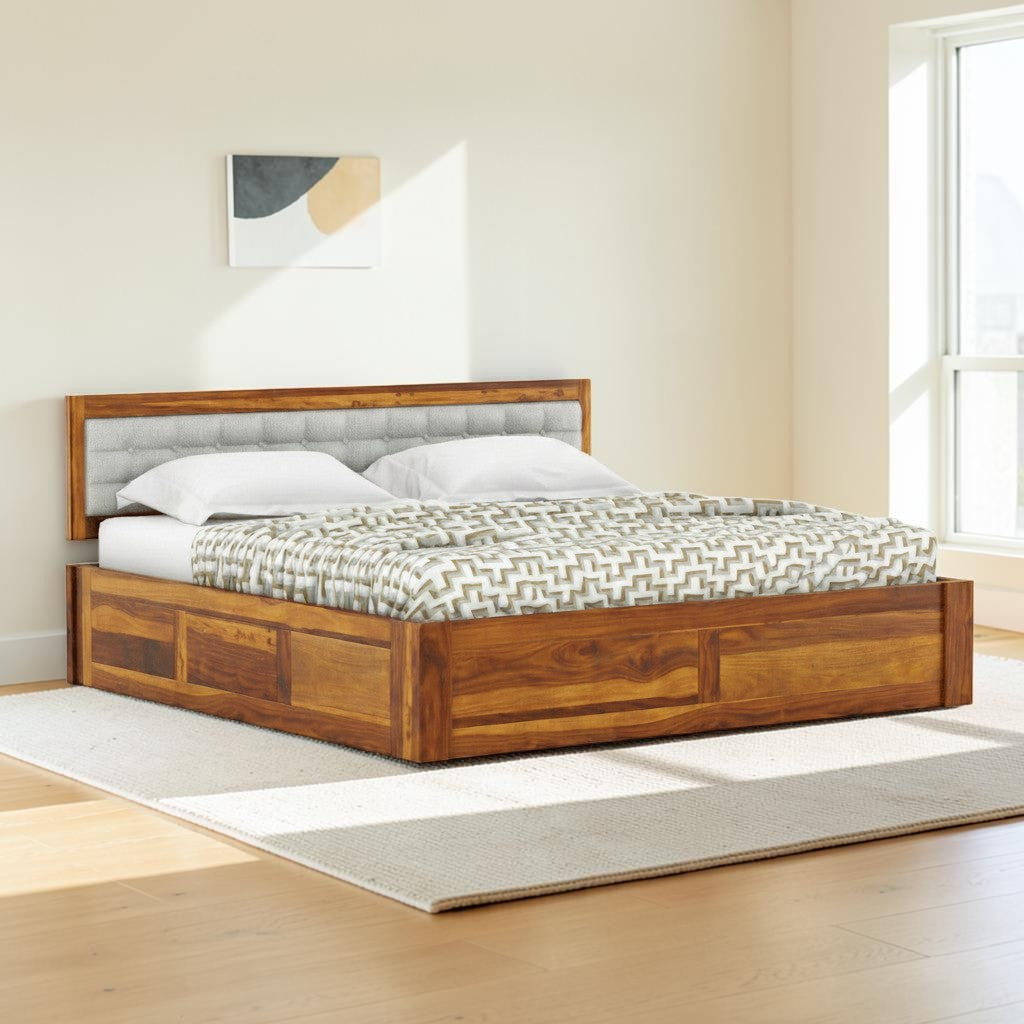 Homecrest Thurloe solid Sheesham wood bed featuring a grey cushioned headboard and box storage base in a bedroom setting