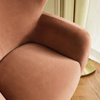 Homecrest Yannick wing-arm accent chair in plush truffle pink velvet with curved armrests on a textured orange rug.