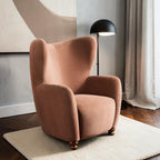 Homecrest Yannick wing-arm accent chair in plush truffle pink velvet with dark turned wooden feet in a modern room.