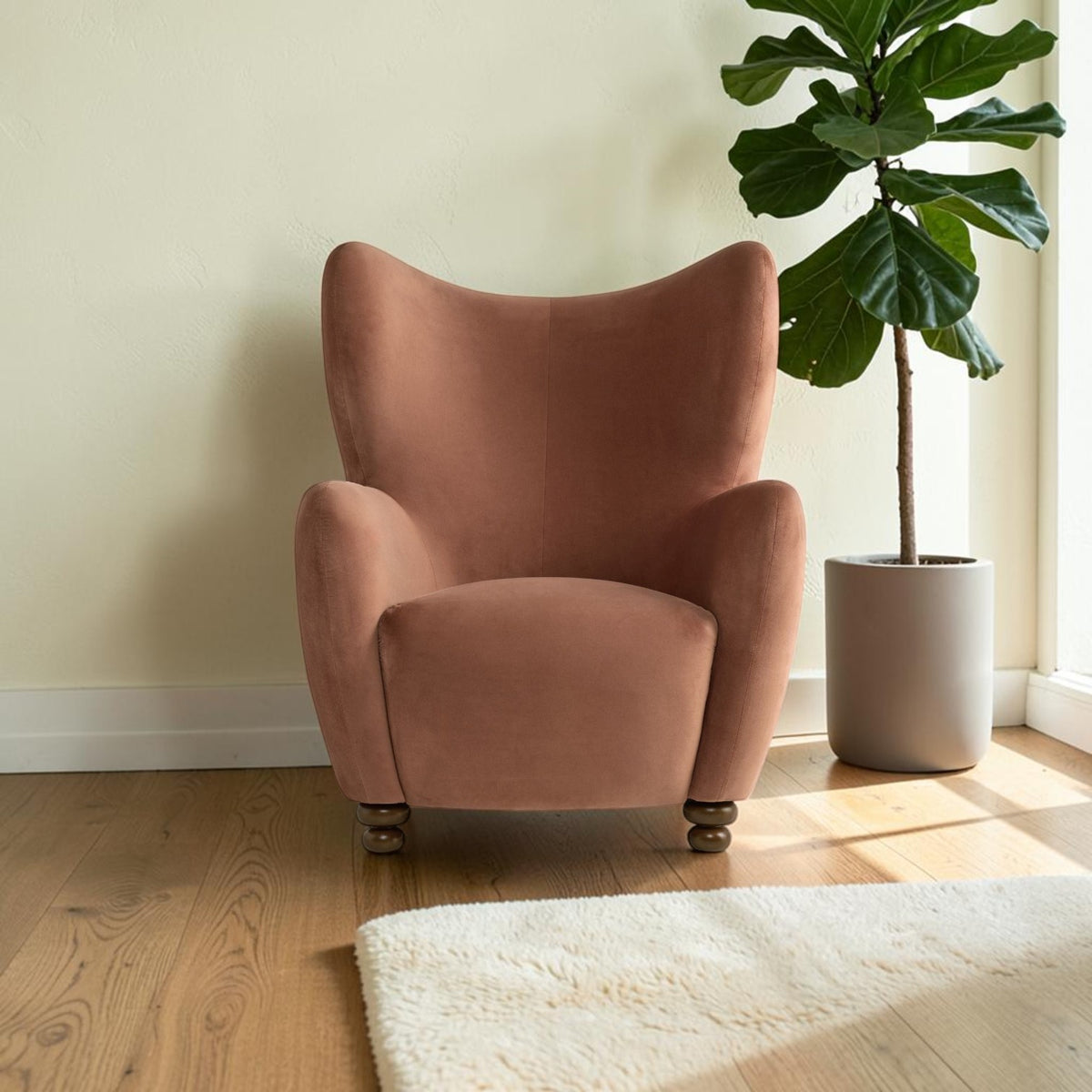 Homecrest Yannick wing-arm accent chair in plush truffle pink velvet with dark turned wooden feet in a bright room.